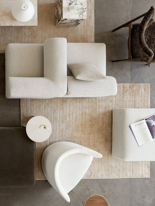 Top-down view of the Houkime Rug styled in a minimalist living room with a white sofa, chairs, and marble side table.