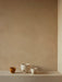 A trio of Hydrous Planters in varying sizes. One medium ochre planter and two off-white planters on a beige stone shelf.