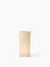 An angled tall Ignus Flameless Candle in off-white bone china, glowing with a warm light on a white background.