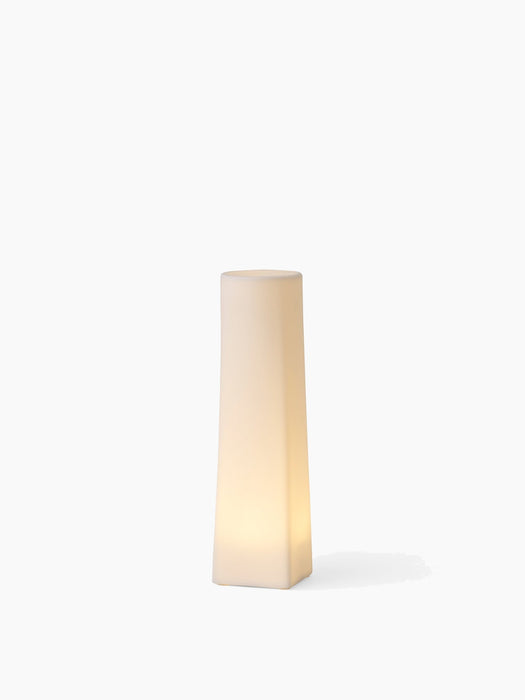 A single, tall Ignus Flameless Candle, lit up to cast a warm glow. It has a square base and is shown on a white background.