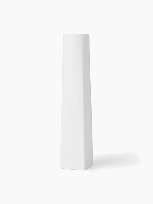A tall, slender, white sculptural Ignus Flameless Candle made from matte bone china, shown at an angle on a white background.