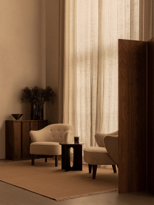 A living room featuring two cream Ingeborg Lounge Chairs, a dark Androgyne Side Table, and a cabinet with a Taper Bowl.