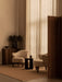 A living room featuring two cream Ingeborg Lounge Chairs, a dark Androgyne Side Table, and a cabinet with a Taper Bowl.