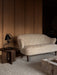 The cream sheepskin Ingeborg Sofa sits in a room with wood panelling, beside a dark wood table with a black Klampenborg Lamp.