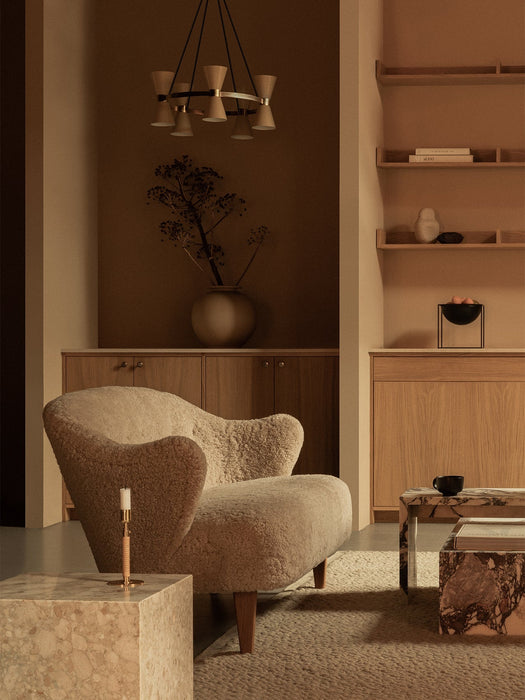 A living room featuring the Ingeborg Sofa in cream sheepskin, beside a Plinth Cubic table and under a Collector Chandelier.