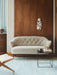 The white sheepskin Ingeborg Sofa on a light blue rug against a wood panelled wall, with a black Twin Table and a Saxe Chair.