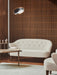 A cream Ingeborg Sofa and matching lounge chair in a room with a slatted wood wall, next to a coffee table with a Kubus 8.