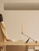 Woman at a dining table with an Interconnect Candle Holder, below a Hashira Linear Pendant, with Ready Dining Chairs nearby.
