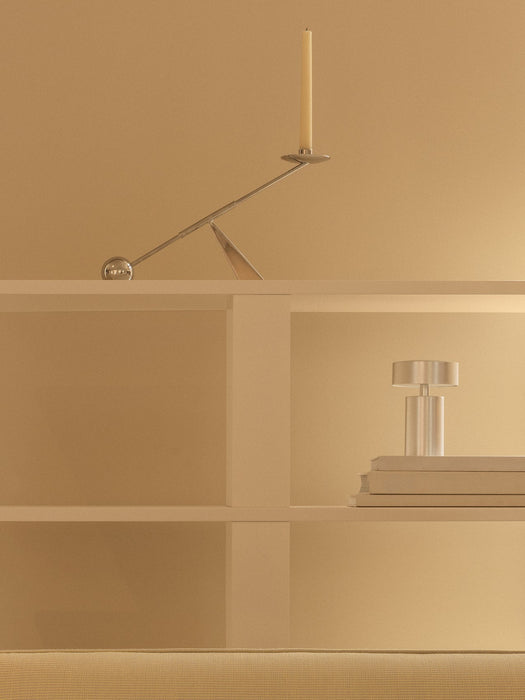 Silver Interconnect Candle Holder and portable Column Table Lamp on minimalist white shelves against a beige wall.