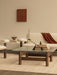 A modern living room with a cream bouclé sofa, glass coffee table with a sculptural black candlestick, and warm earthy tones.