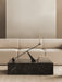 A black marble Plinth Low table in front of an Eave Modular Sofa. On the table is an Interconnect Candle Holder and books.