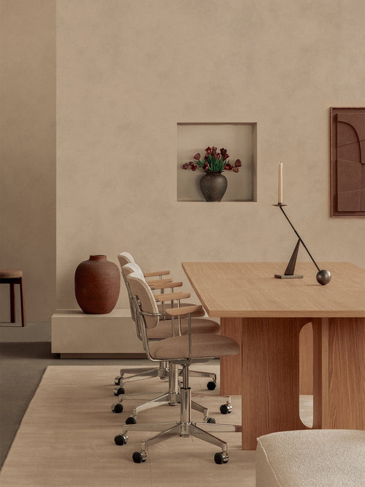 Androgyne Dining Table and Co Task Chairs in a beige room with an Interconnect Candle Holder, Passage Stool and vases.