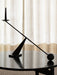 A sculptural black Interconnect Candle Holder with a matching black candle, balanced on a black wooden Passage Lounge Table.