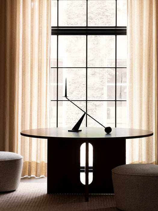 A black Interconnect Candle Holder on a dark wood Androgyne Dining Table with Cairn Poufs and a Houkime Rug by a window.