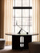 A black Interconnect Candle Holder on a dark wood Androgyne Dining Table with Cairn Poufs and a Houkime Rug by a window.