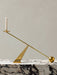 The polished brass Interconnect Candleholder with a white candle, resting on a black and white marble Plinth Low.