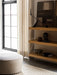 An oak Zet Storage System with an Interconnect Candle Holder and Echasse Bowl. A Cairn Pouf and Gravel Rug are by a window.