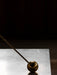 Close-up detail of the Interconnect Candle Holder's polished brass sphere and stem resting on a grey marble surface.