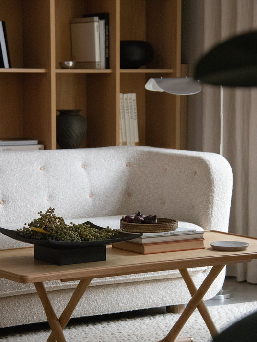 A Jäger Lounge Table in a living room setting, placed in front of a white Vilhelm Sofa with a bookshelf in the background.