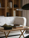 A Jäger Lounge Table in a living room setting, placed in front of a white Vilhelm Sofa with a bookshelf in the background.
