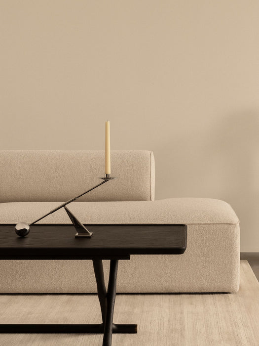 A black Jäger Lounge Table with an Interconnect Candle Holder, placed in front of a beige Eave Modular Sofa in a calm room.