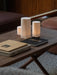 A close-up of the wooden Jäger Lounge Table, styled with books and three glowing Ignus Flameless Candles on a white rug.