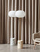 The JWDA Floor Lamp shown in two versions: white marble with a bronzed stem and travertine with a brushed brass stem.