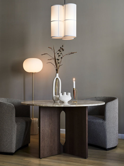 The JWDA Floor Lamp illuminates a dining setting with an Androgyne Dining Table, flanked by two upholstered Tearoom chairs.