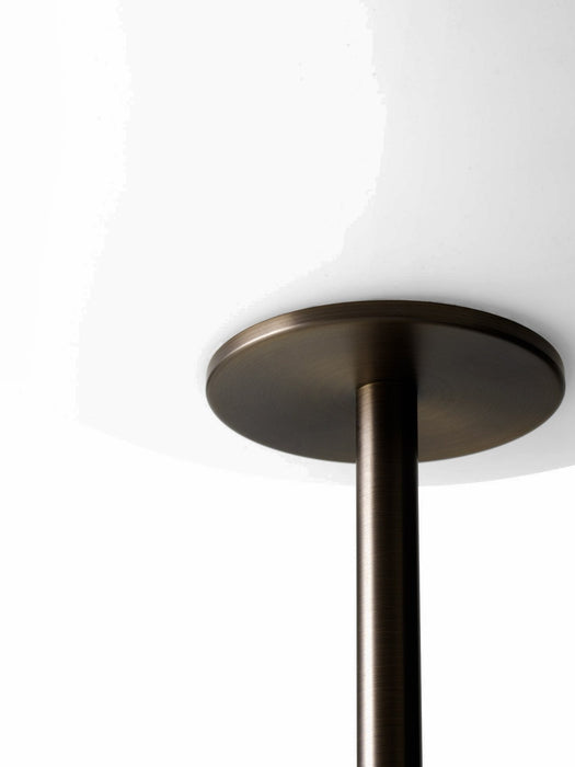 A close-up shot of the JWDA Floor Lamp showing the point where the bronzed brass stem connects to the white opal glass shade.