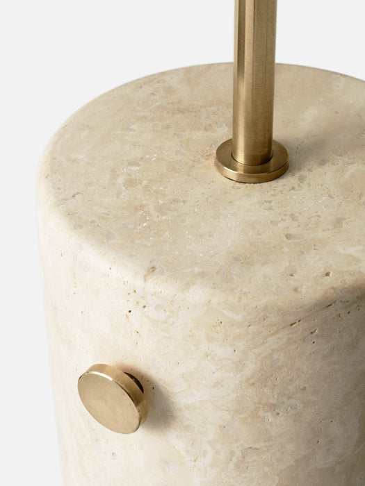 A close-up of the JWDA Floor Lamp, detailing the porous texture of its travertine stone base and brushed brass dimmer switch.