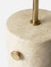 A close-up of the JWDA Floor Lamp, detailing the porous texture of its travertine stone base and brushed brass dimmer switch.