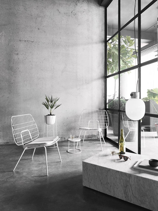 The JWDA Metallic Pendant Lamp hangs over a Plinth marble table. The minimalist room also features white String Chairs.