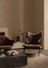 The brown sheepskin Knitting Lounge Chair in a modern room with a marble Plinth table, Ingeborg Sofa, and Stance Vase.