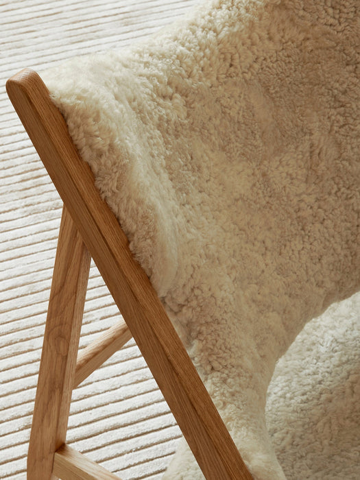 Close-up from above of the Knitting Lounge Chair, highlighting the plush sheepskin seat and the natural oak wood frame.