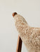 A close-up of the Knitting Lounge Chair, highlighting the fluffy sheepskin upholstery and the smooth, warm wooden frame.