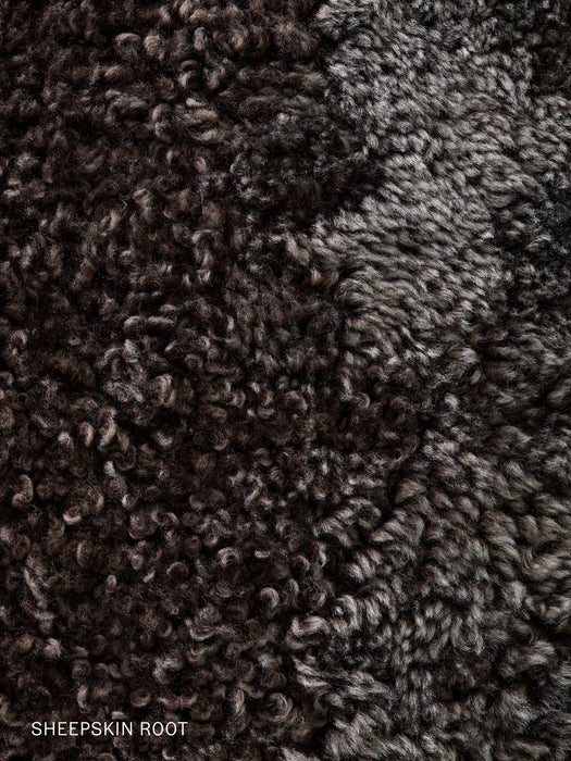 A detailed close-up of the dark brown, curly Sheepskin Root textile, an upholstery option for the Knitting Lounge Chair.