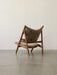 Three-quarter back view of the Knitting Lounge Chair in brown Sheepskin with a dark wood frame, set in a minimalist room.