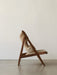 Side view of the Knitting Lounge Chair, Sheepskin, with its dark walnut A-frame and plush, light brown sheepskin upholstery.