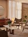 A warmly lit living room with two Knitting Lounge Chairs in brown sheepskin, a marble coffee table, and a wooden sideboard.