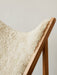 Close-up detail of the Knitting Lounge Chair, showing the fluffy white sheepskin seat set within the solid natural oak frame.