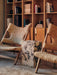 A living room with two Knitting Chairs, a marble Plinth table with a Duca Candle Holder, set on a Houkime Rug by a bookcase.
