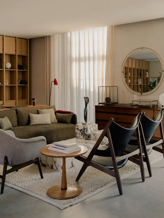 Sunlit living room with black Knitting Chairs, grey Harbour Lounge Chair, green Offset Sofa, Nimbus Mirror, and Plinth cubes.