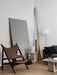 The Knitting Lounge Chair in brown leather and dark wood, styled in a minimalist room with a sofa, lamp, and side table.