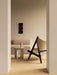 Side view of the Knitting Lounge Chair in black oak in a beige room with the Eave Modular Sofa and Androgyne Side Table.