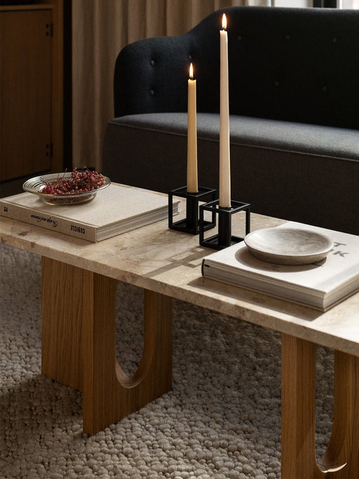 A living room with two lit candles in black Kubus 1 candleholders on a coffee table, with the Constance Sofa behind.