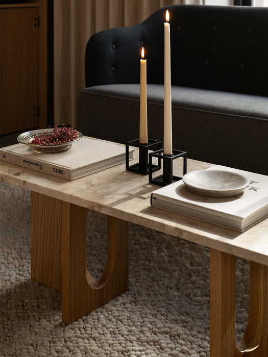 A living room with two lit candles in black Kubus 1 candleholders on a coffee table, with the Constance Sofa behind.