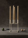 The ivory Kubus 4 candle holder with four tall beige candles, styled on a dark textured surface with a lime and a mushroom.