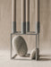 The Kubus 4 zinc candle holder with four taupe candles is styled with two smooth grey stones placed inside its square frame.