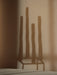 Atmospheric close-up showing the distinct shadow of the Kubus 4 candleholder and four tall candles cast on a warm-toned wall.