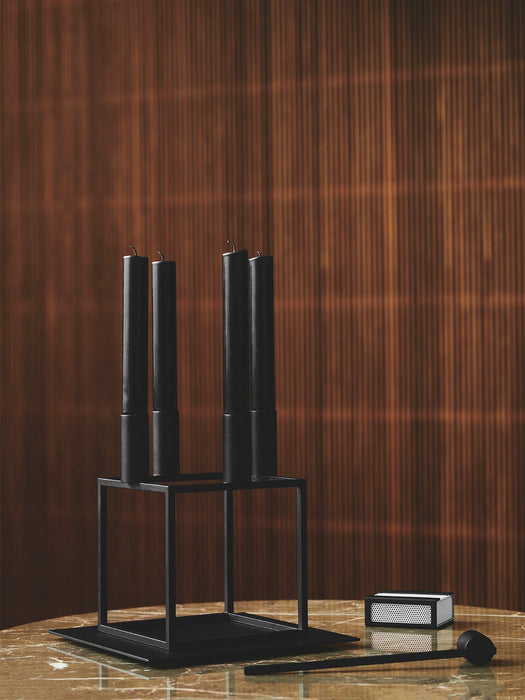 Black Kubus 4 candle holder with four black candles on a Kubus Base, with a Matchbox Cover and Snuffer on a marble tabletop.